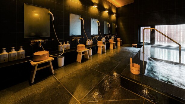A modern bathroom with multiple sinks, wooden stools, and hand sanitizer dispensers. - Super Hotel Tokyo Kinshicho Ekimae (Tokyo)