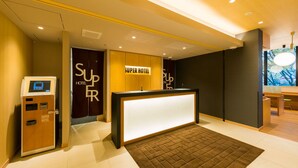A hotel reception area with a reception desk, a self-service kiosk, and a large window with a view. - Super Hotel Tokyo Kinshicho Ekimae (Tokyo)