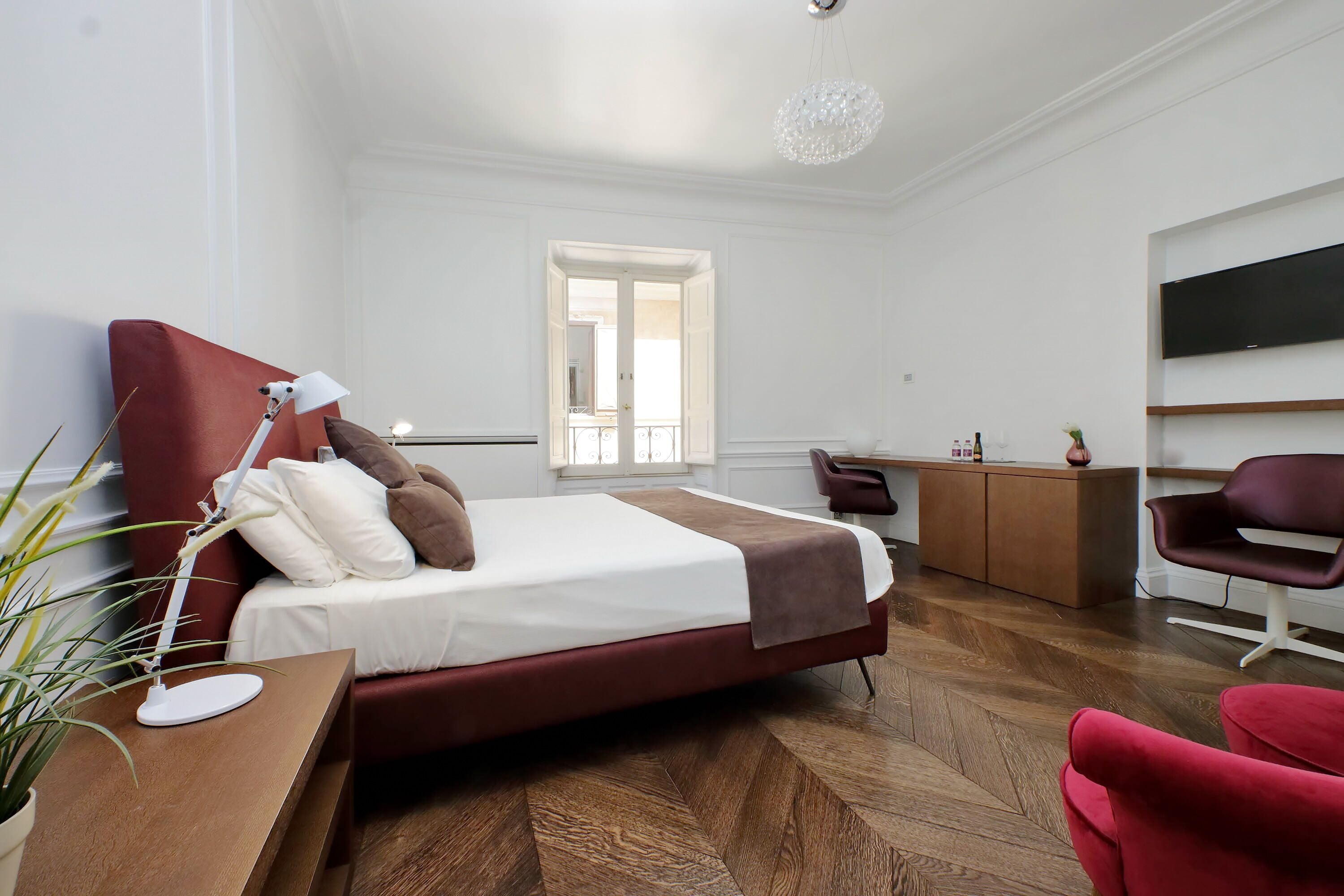 Une chambre d’hôtel moderne dotée d’un grand lit, d’un bureau, d’une chaise, d’une télévision et offrant une vue sur le balcon.