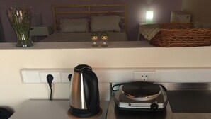 Una kitchenette equipada con un refrigerador, una tetera y un tostador.