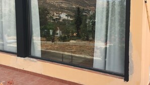 Un edificio con amplios ventanales, un patio empedrado y vistas a un paisaje montañoso.