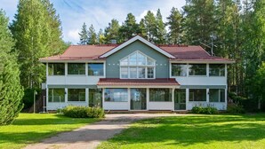 Ein zweistöckiges Haus mit rotem Ziegeldach, großen Fenstern und einer überdachten Veranda.