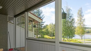 Eine überdachte Terrasse mit Blick auf einen See und Bäume.