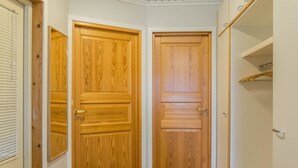 Ein Flur mit zwei Holztüren, einem Podest, das zu einem Schrank führt, und einer grünen Matte auf dem Boden.