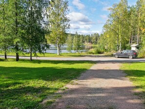 Un chemin de gravier mène à un lac, et une voiture est garée à proximité.