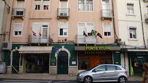 A building with multiple balconies, a restaurant named 'Ponte Velha' on the ground floor, and a silver car parked in front. - Hospedaria D. Damélio (Lisbon)