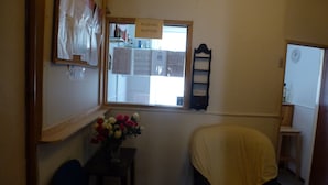 A reception area with a window, a reception sign, a wall-mounted shelf, and a chair. - Hospedaria D. Damélio (Lisbon)