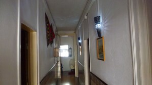 A hallway with a tiled floor, a wooden door on the left, and a framed picture on the right wall. - Hospedaria D. Damélio (Lisbon)