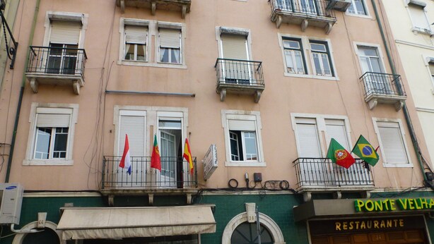A building with multiple balconies, a restaurant named "Ponte Velha Restaurante," and several flags. - Hospedaria D. Damélio (Lisbon)