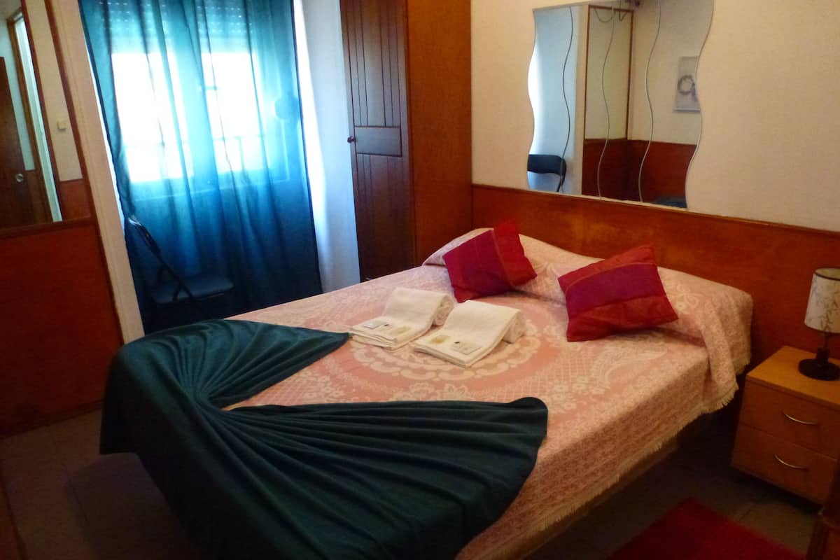 Ein Hotelzimmer mit Bett, Nachttisch, Lampe und Spiegel.