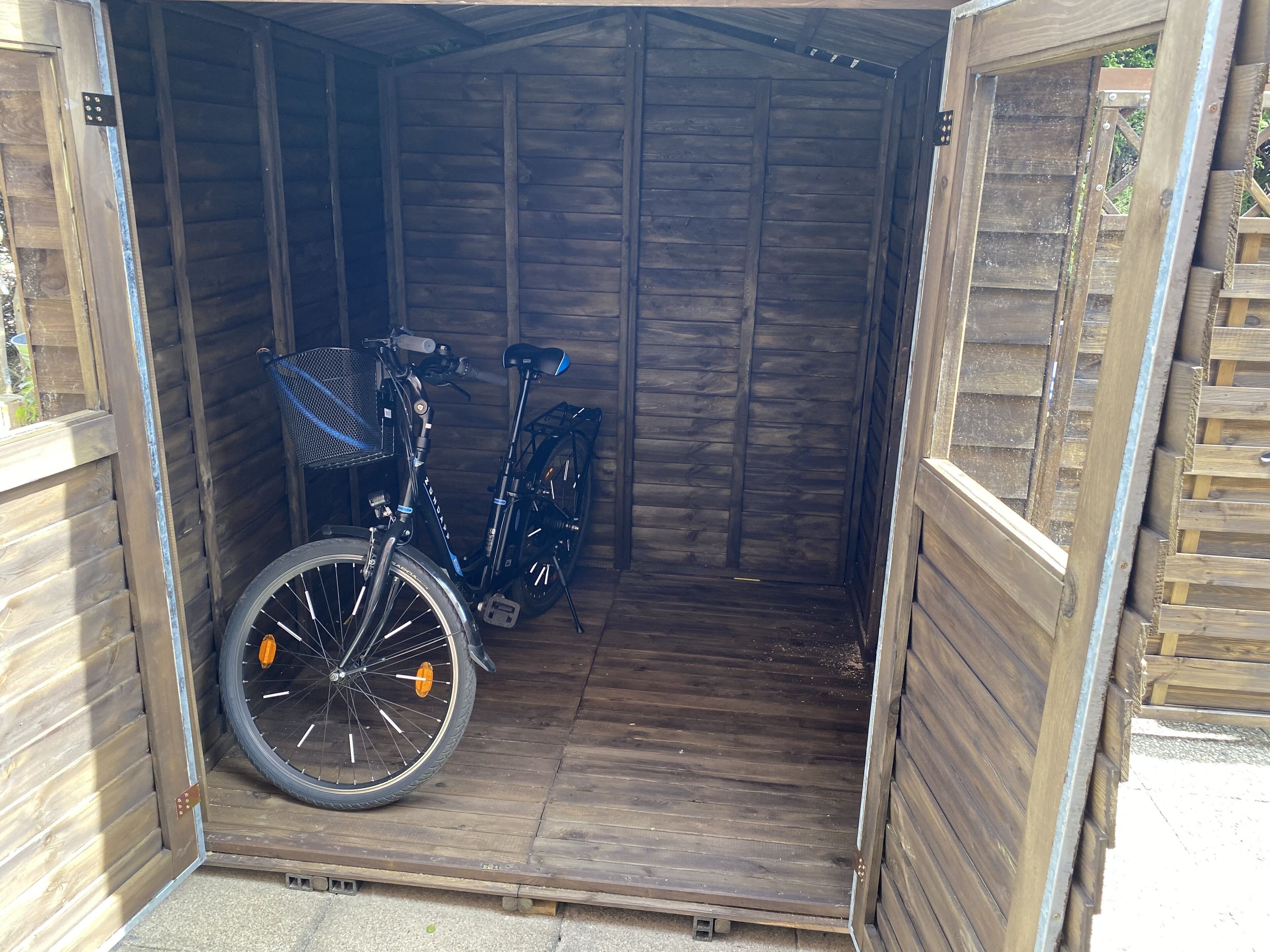 Ein kleines, hölzernes Gartenhaus mit einem Fahrrad darin.