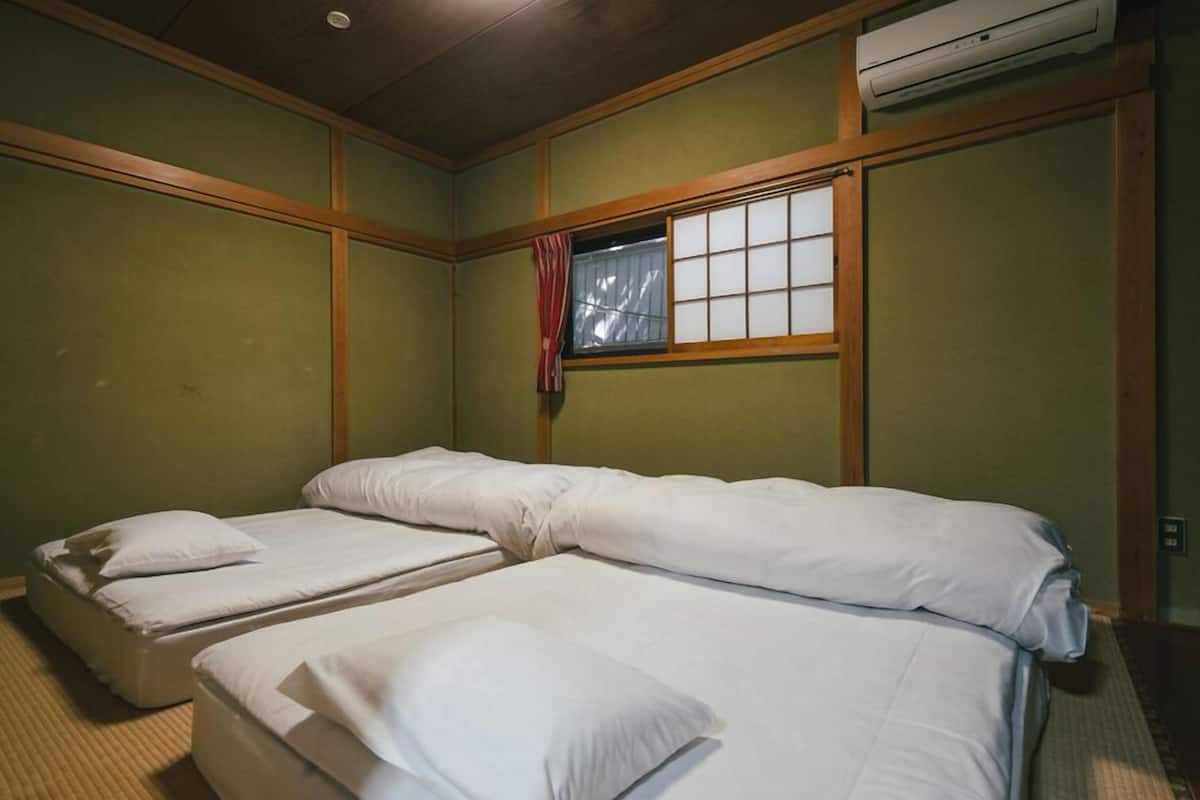 Una habitación con dos camas, una ventana con cortina y un equipo de aire acondicionado.