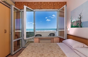 Una habitación de hotel con cama, escritorio y vista al mar.