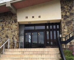 Fachada de piedra con una entrada y un conjunto de escalones que llevan a ella, además de un cartel con caracteres chinos.
