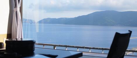 A room with a view of a large body of water and distant mountains.