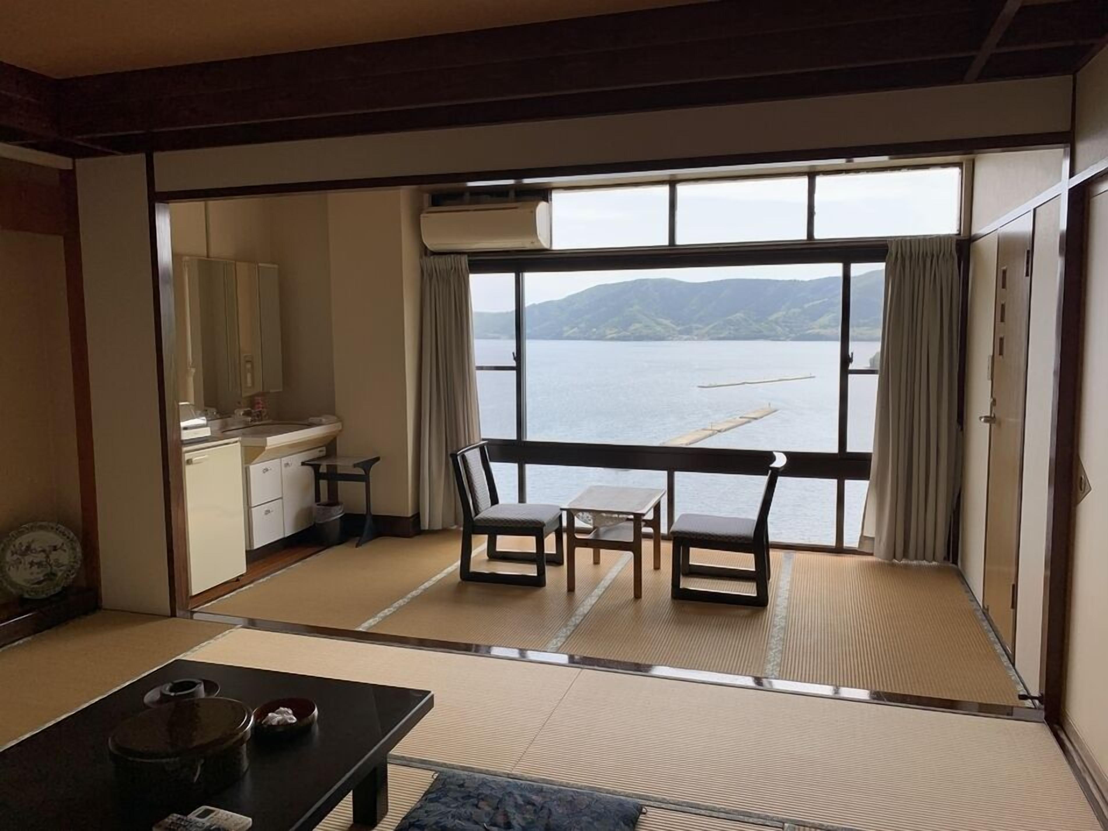 Habitación con vista a un lago, un escritorio, una silla y una pequeña mesa con tetera.