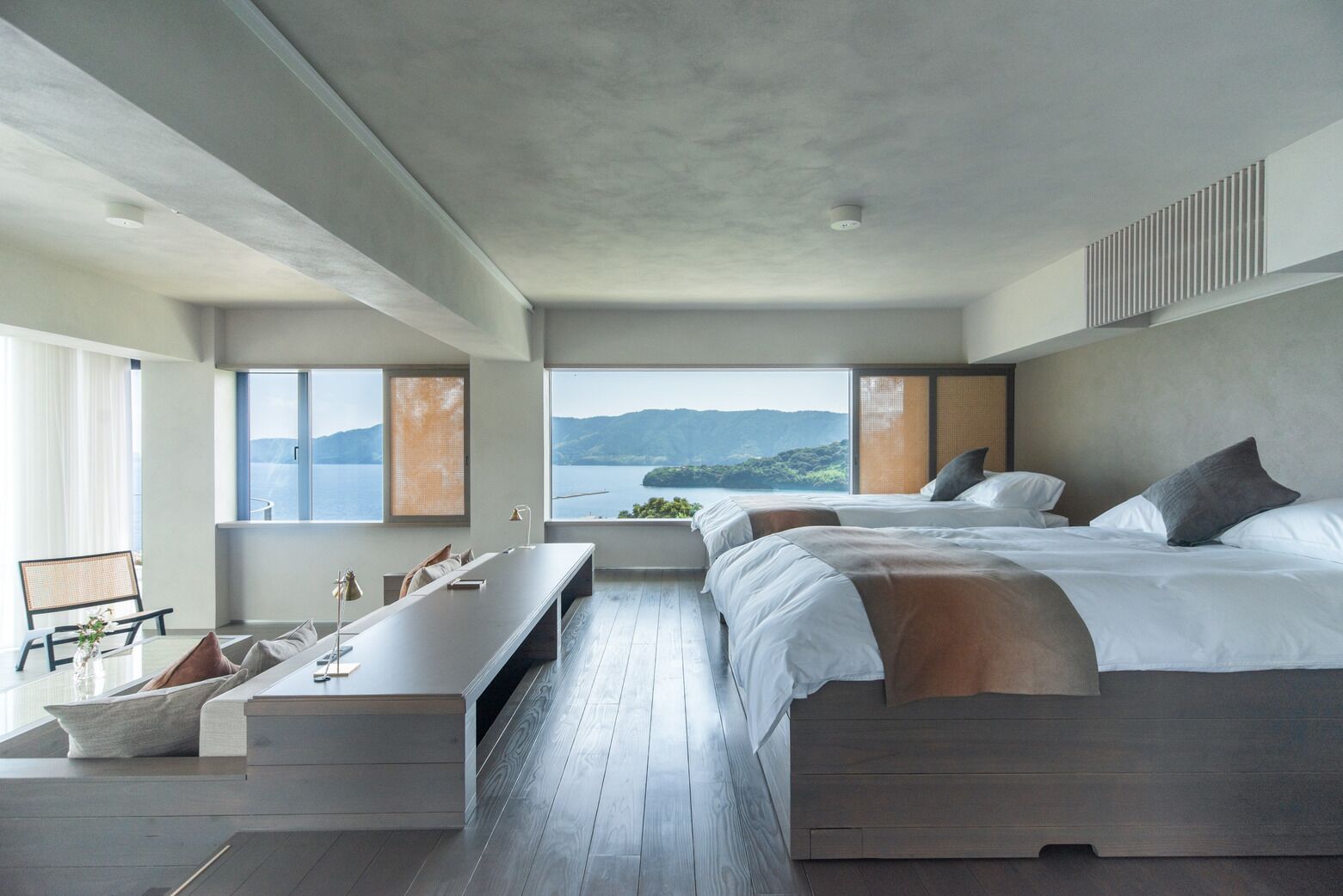 Una habitación de hotel moderna con una cama grande, un escritorio y vistas al mar.
