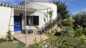 A house with a covered patio, a blue door, and a staircase leading to a second floor.