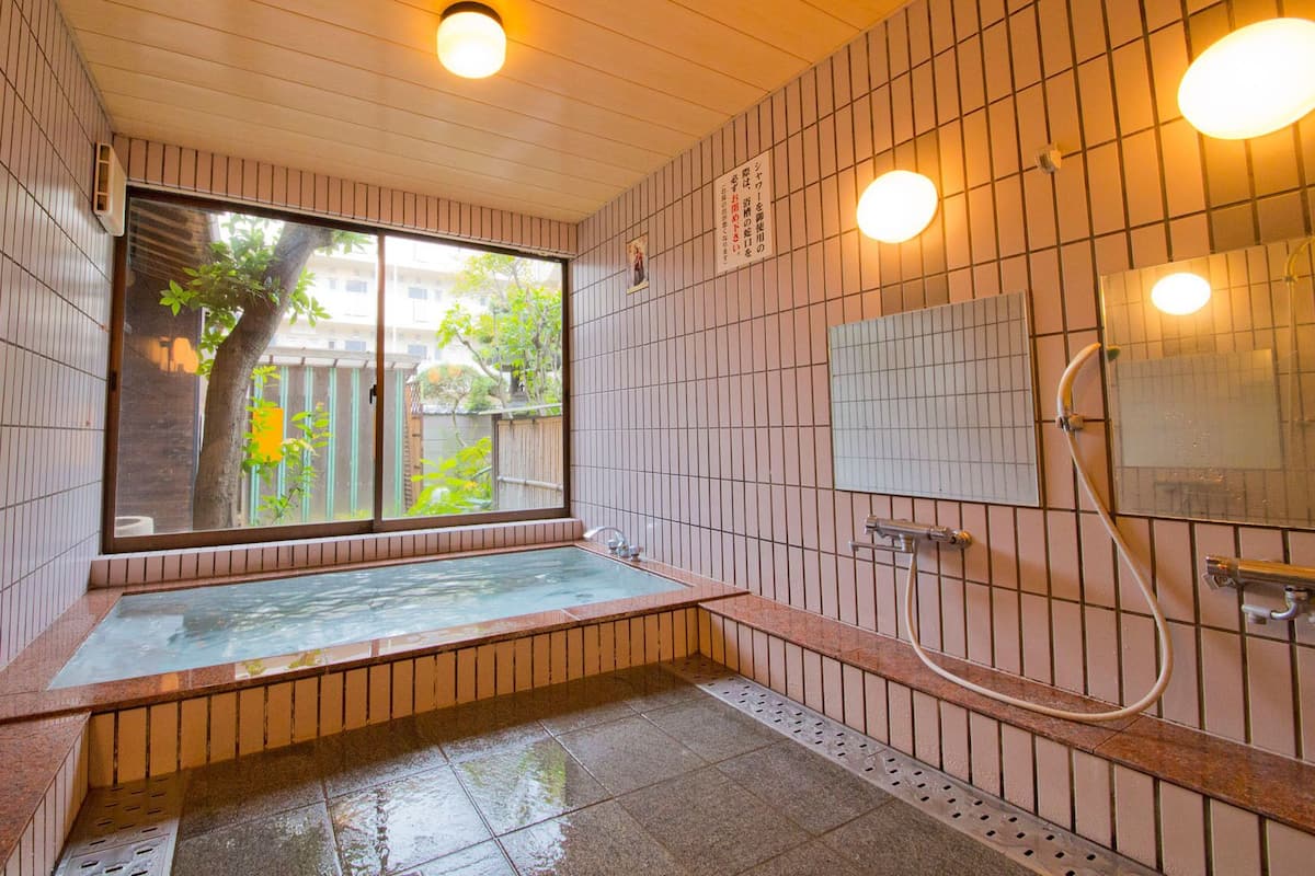 A traditional Japanese-style bath with a sliding door, a small window, and a tiled wall.