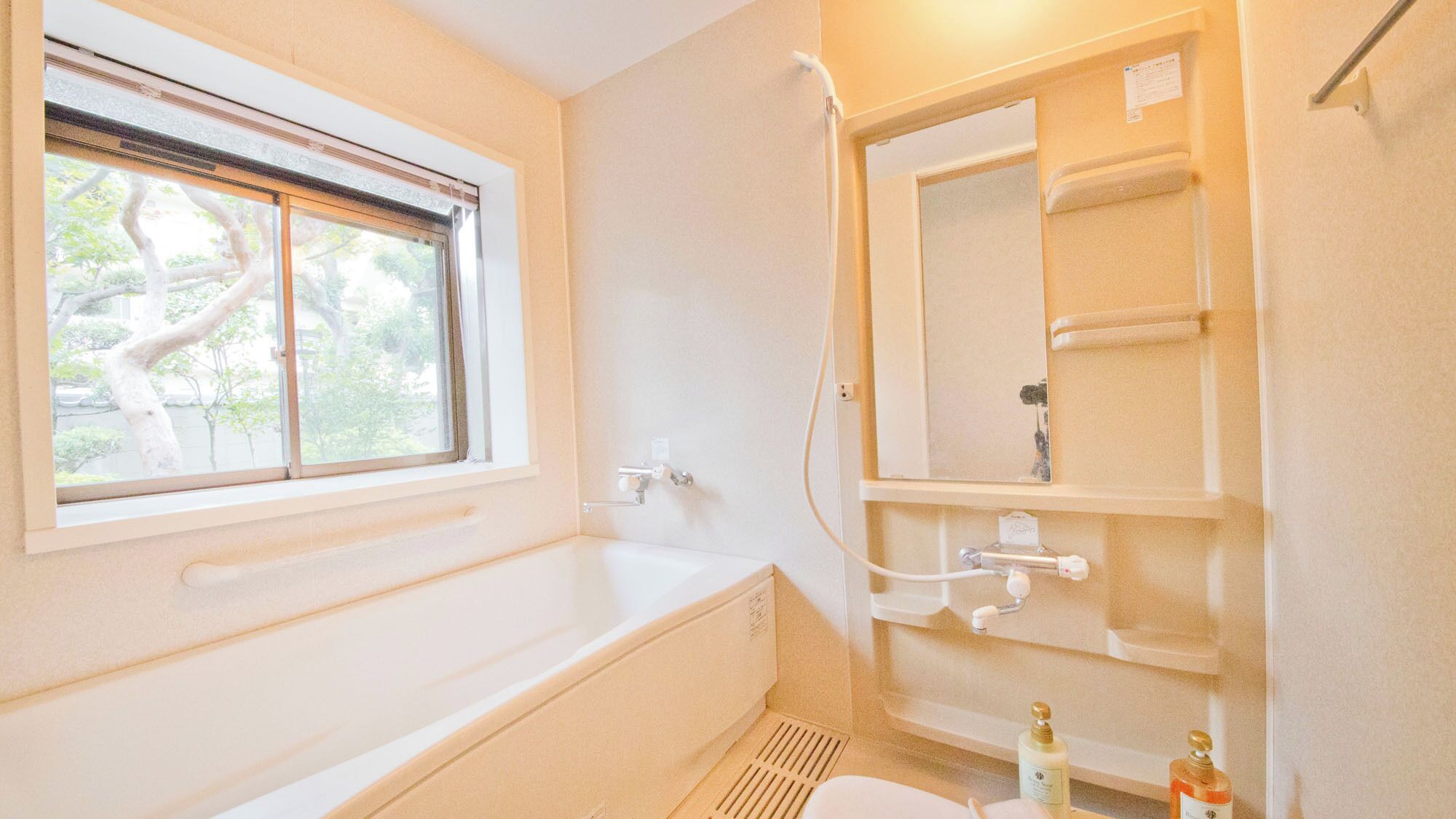 A bathroom with a bathtub, a window, a shower, and a toilet.