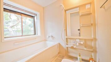 A bathroom with a bathtub, a window, a shower, and a toilet.