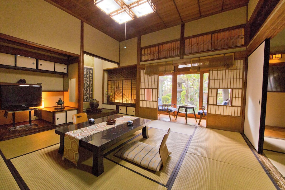 A traditional Japanese room with tatami flooring, a low table, a television, and sliding doors.