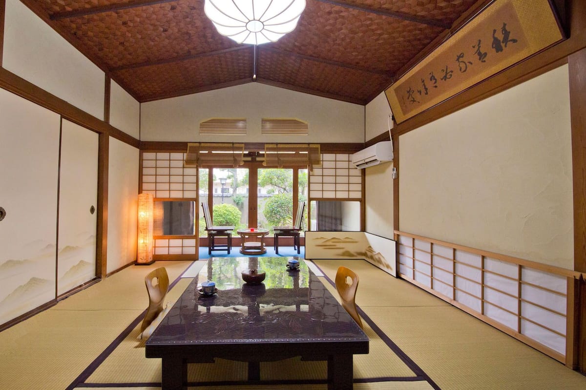 A traditional Japanese room with tatami flooring, a low table, and sliding doors.