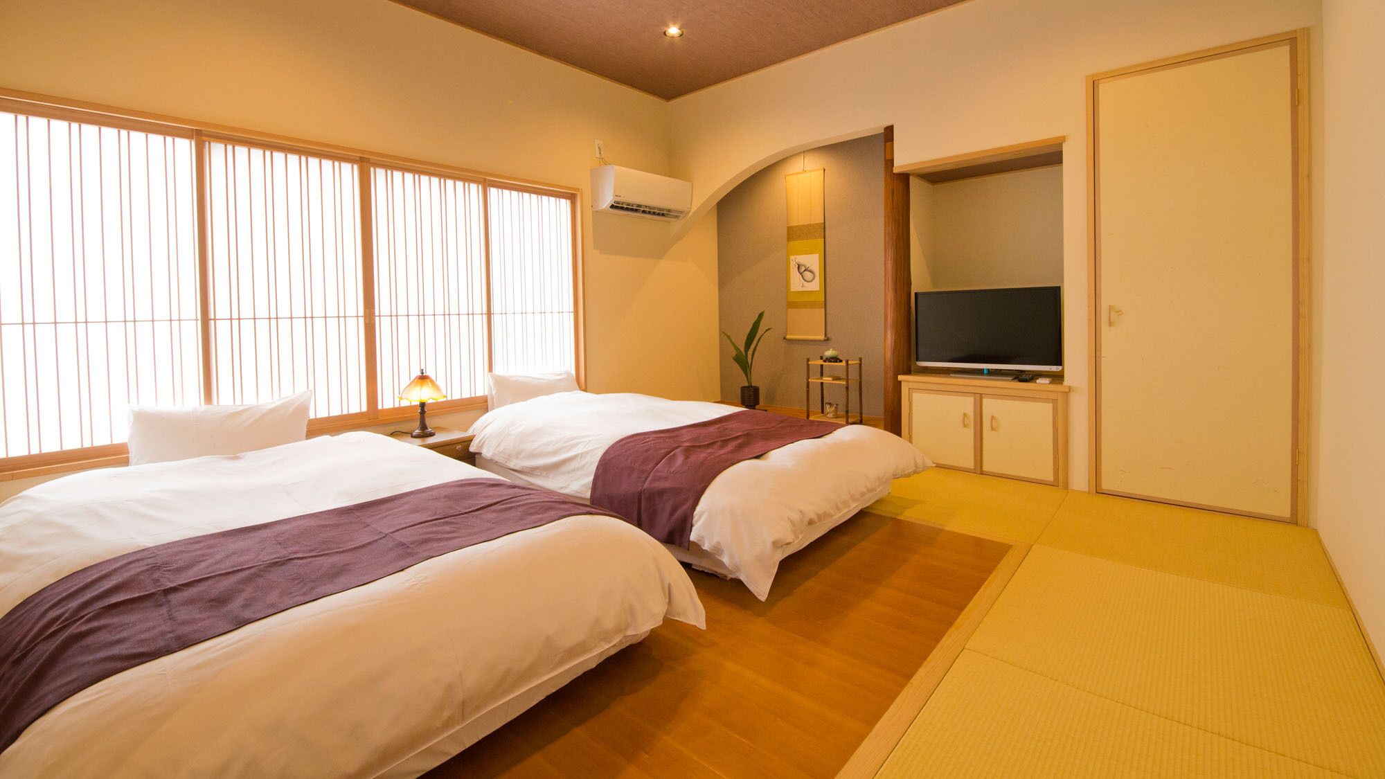 A hotel room with two beds, a television, and a small cabinet.