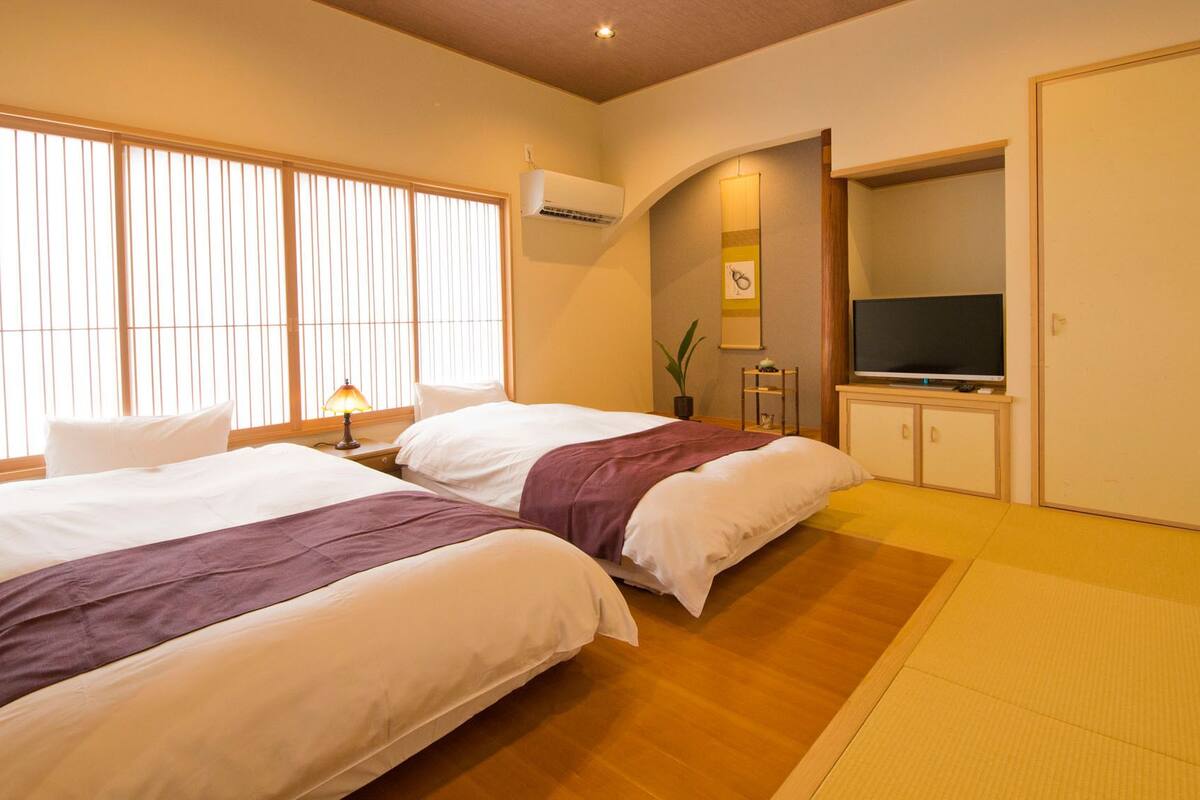 A hotel room with two beds, a television, and a small cabinet.