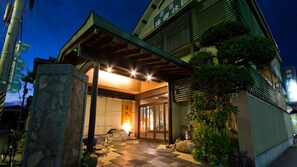 Um edifício japonês tradicional com entrada em pedra, varanda coberta e interior bem iluminado.