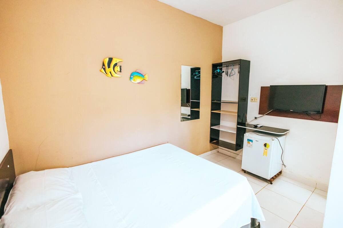 A hotel room with a bed, a wardrobe, a television, and a small refrigerator.