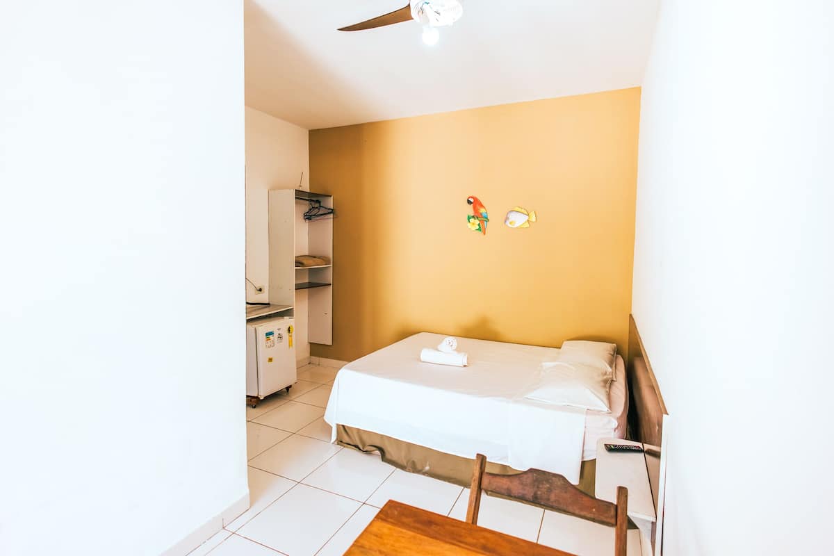 A hotel room with a bed, a wooden chair, a ceiling fan, and a wall with a fish decal.