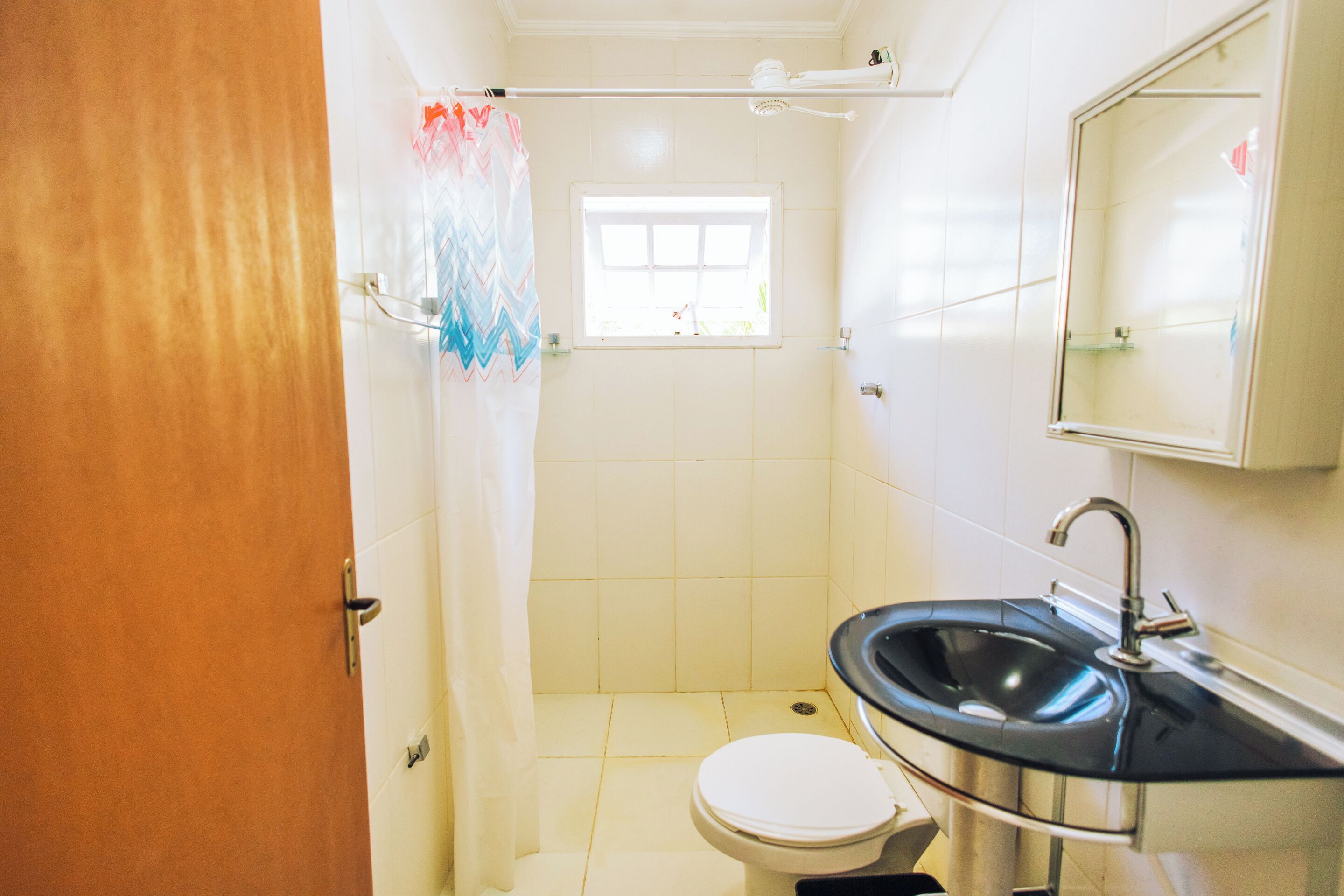 Ein Badezimmer mit Toilette, Waschbecken, Dusche und einem Fenster.