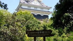 Eine traditionelle japanische Burg mit einem Schild, das ihren Namen und ihre historische Bedeutung ausweist.