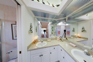 A bathroom with two sinks, a large mirror, and a ceiling fan.
