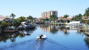 A marina with boats docked, a waterway, and buildings in the background. - 16316 Tortuga (Bokeelia)