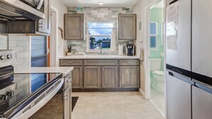 A modern kitchen with a large stove, wooden cabinets, a window, and a refrigerator. - 16316 Tortuga (Bokeelia)