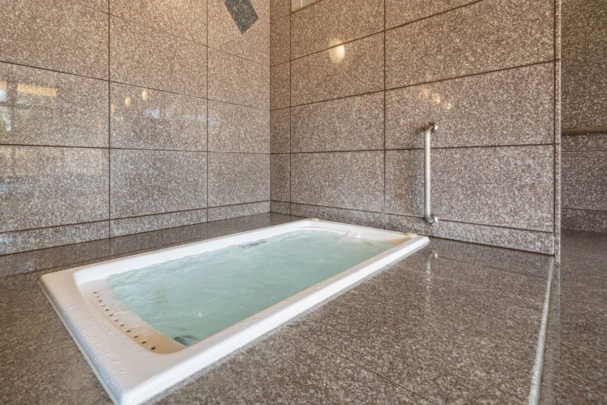 A spa area with a rectangular hot tub, tiled walls, and a metal handrail.