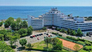 A large hotel with multiple floors, a parking lot, and a tennis court. - HOTEL OPAL Cap Aurora (Jupiter)