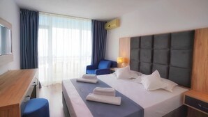 A hotel room with a bed, a desk, a chair, and a TV. - HOTEL OPAL Cap Aurora (Jupiter)