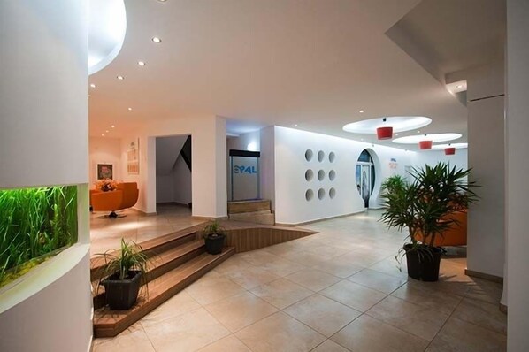 Un vestíbulo moderno con una recepción, una escalera y una pared con recortes circulares.