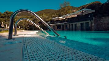 Ein Schwimmbecken mit Metallhandlauf und gefliestem Beckenrand.