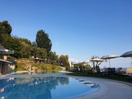 Una piscina al aire libre, sombrillas, tumbonas