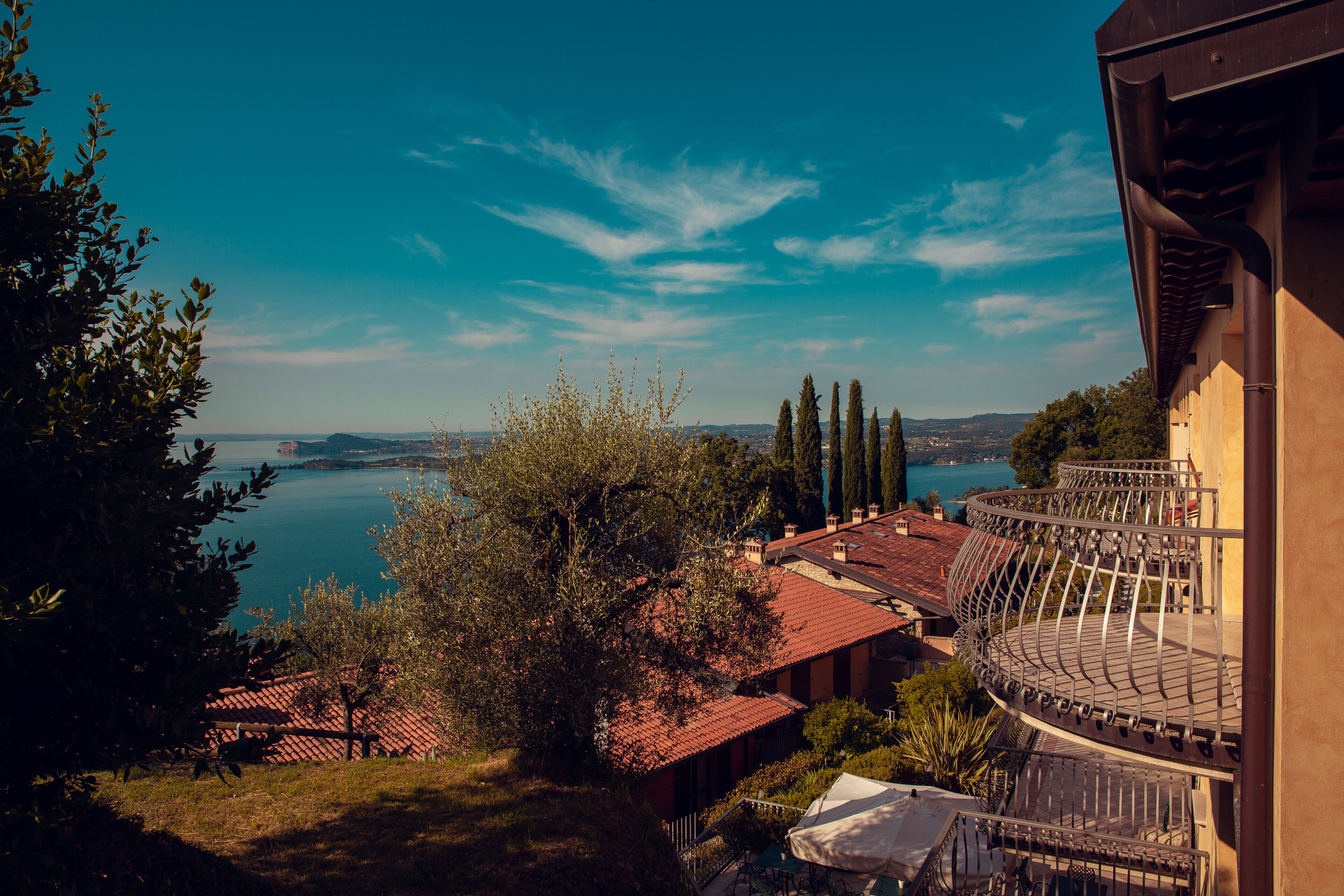 A view of a building with a balcony overlooking a body of water and distant hills.