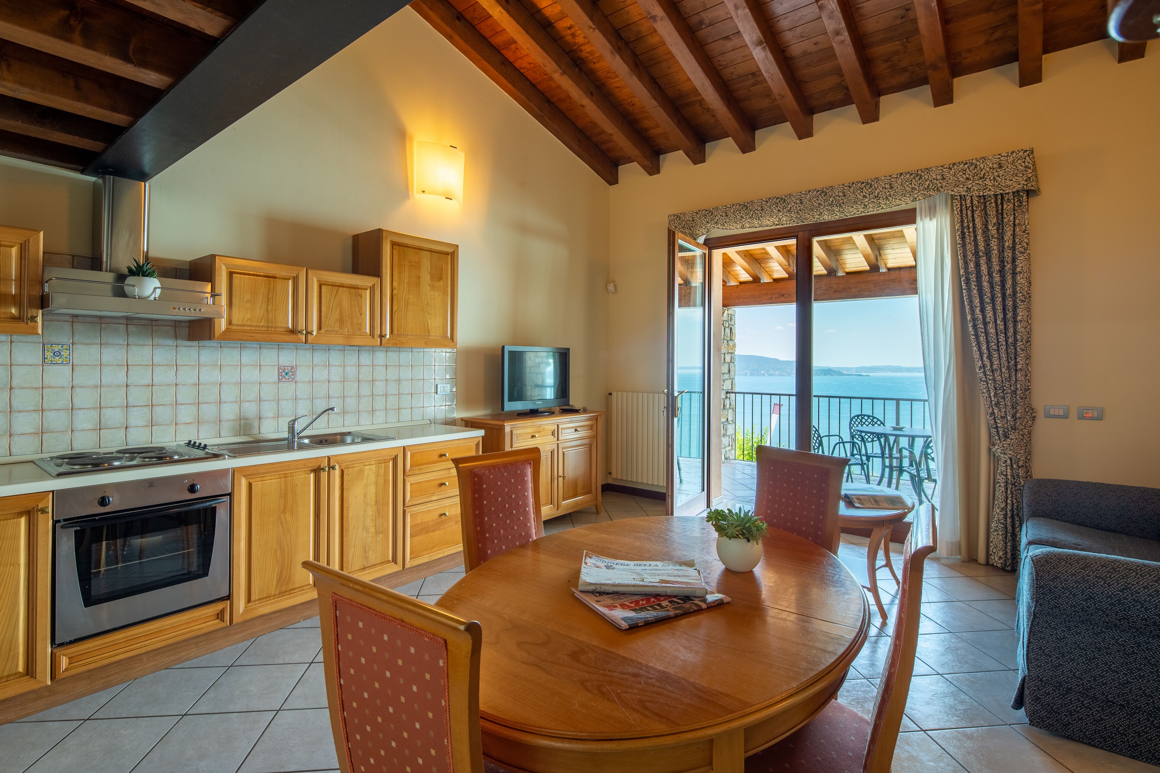A kitchen with wooden cabinets, a stove, and a dining area with a table and chairs.