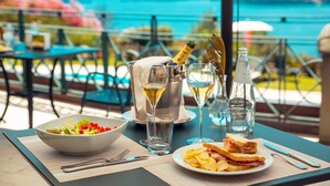 Una mesa servida con ensalada, sándwich, copas de vino y una botella de champán, con vistas a un paisaje idílico.