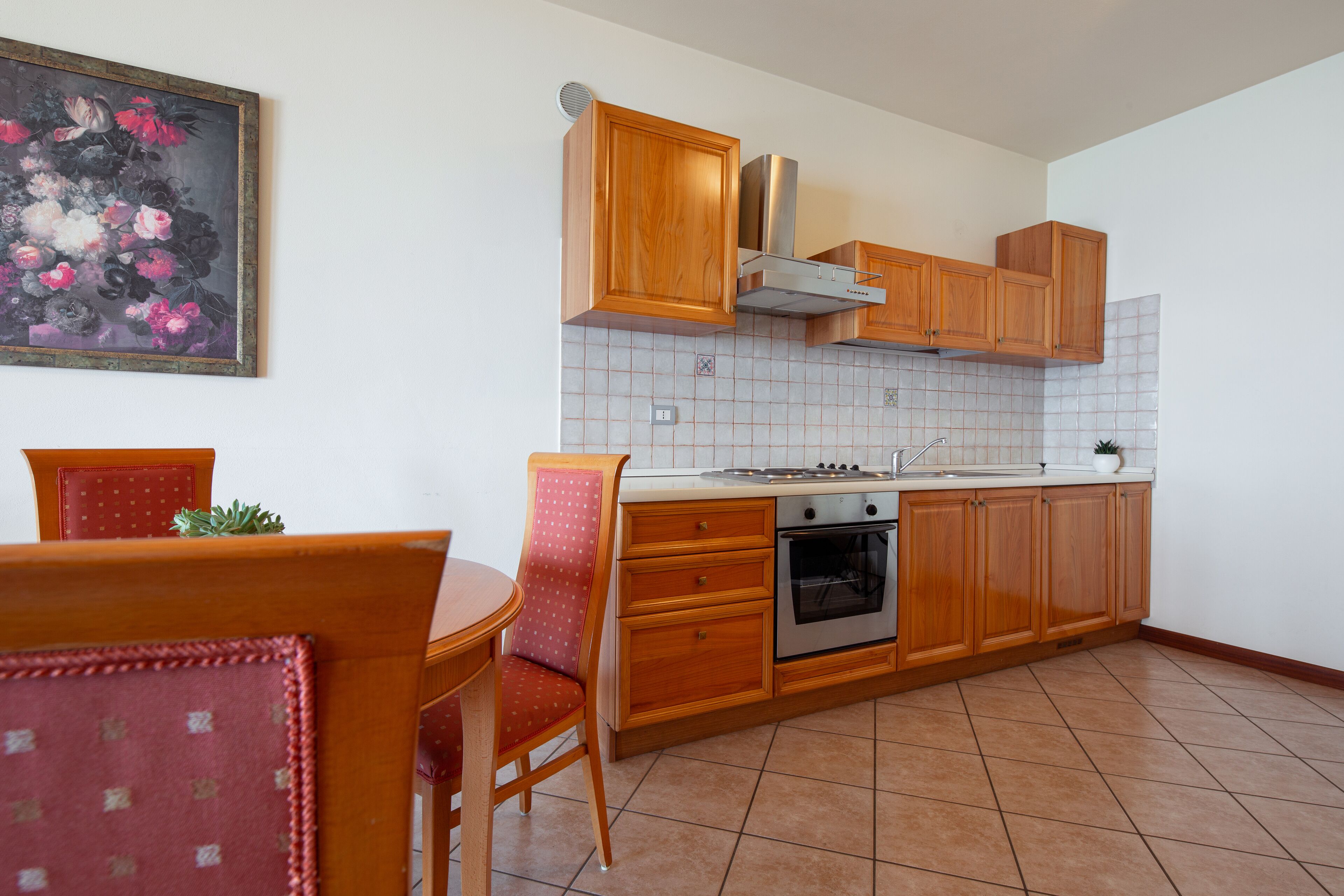 A kitchen with wooden cabinets, a stove, and a dining table with chairs.