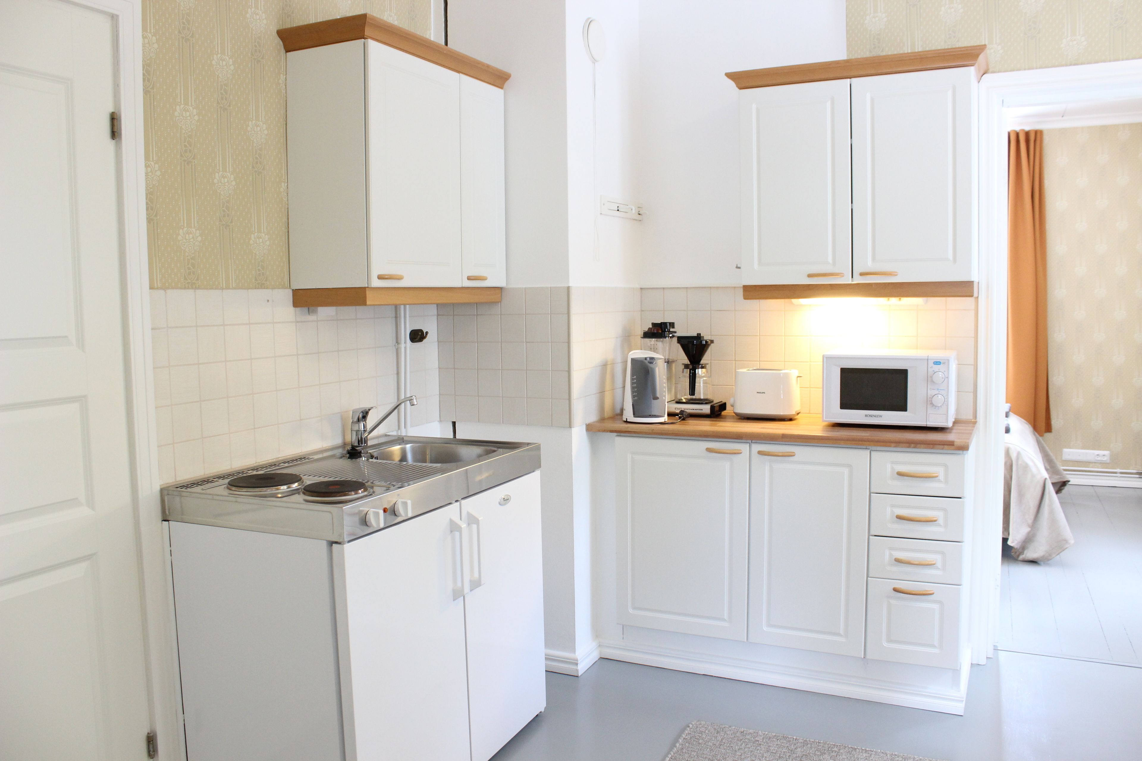 A compact kitchen with white cabinets, a built-in stove, and a microwave.