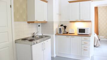 A compact kitchen with white cabinets, a built-in stove, and a microwave.