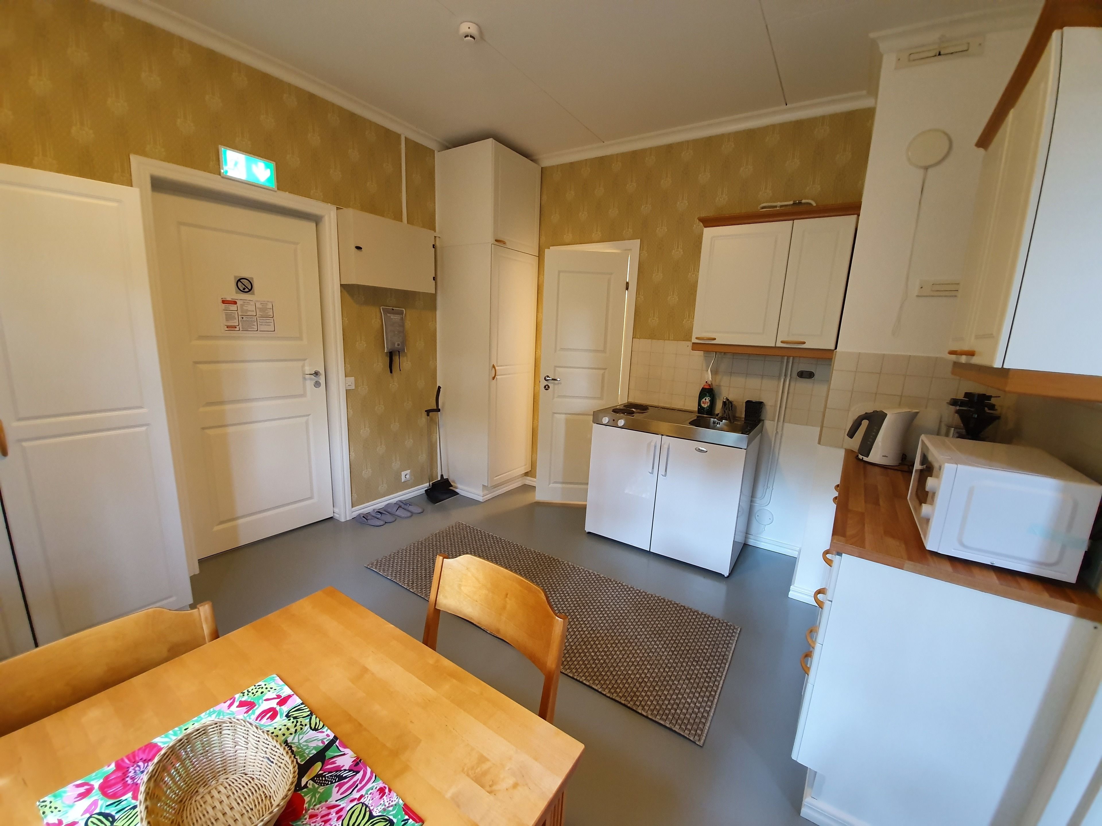 A compact kitchen with white cabinets, a small countertop, and a dining area with a wooden table and chairs.